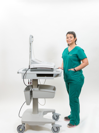 Picture of a smiling female Pulmonary Rehab Nurse standing next to a Pulmonary Rehab Machine Equipment.