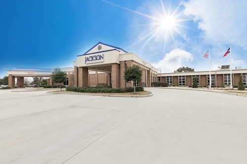 Picture of Jackson County Hospital District showing The Hospital, The Texas and American Flag, and the bright sun shining down from the sky.