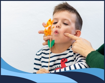 young boy blowing a pinwheel in therapy